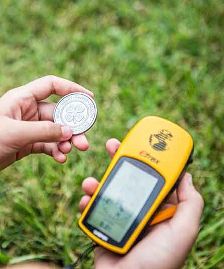 Image of a child holding a coin with a 4-H logo and a Garmin GPS navigator 